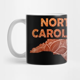 Colorful mandala art map of North Carolina with text in brown and orange Mug